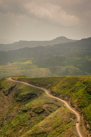 Winding road on a mountainous landscape with lush greenery.