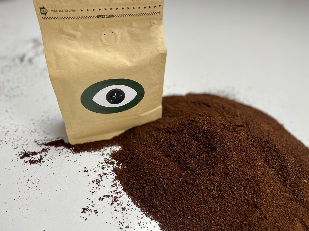Coffee bag with Dark Arts logo next to a pile of ground coffee.