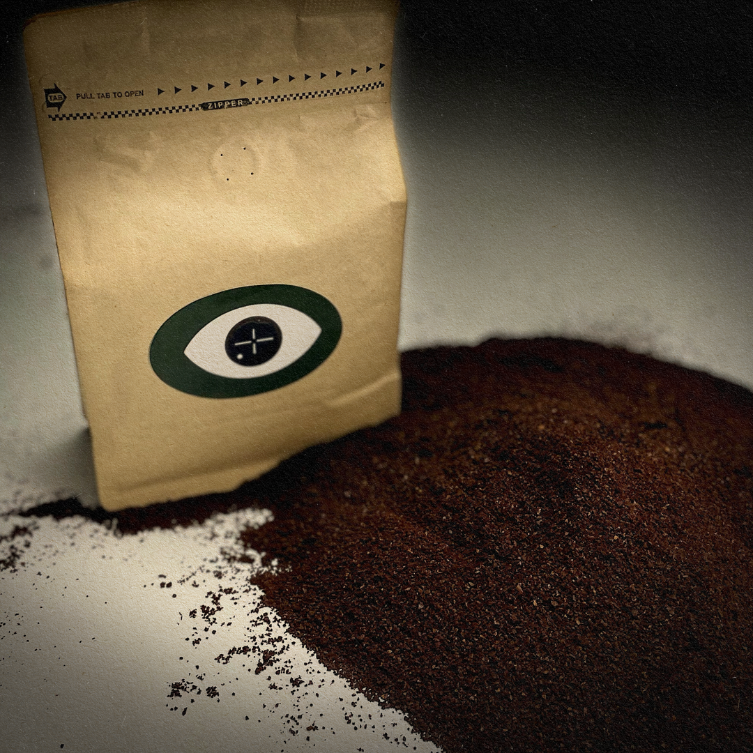 Coffee bag with Dark Arts logo next to a pile of coffee grounds.